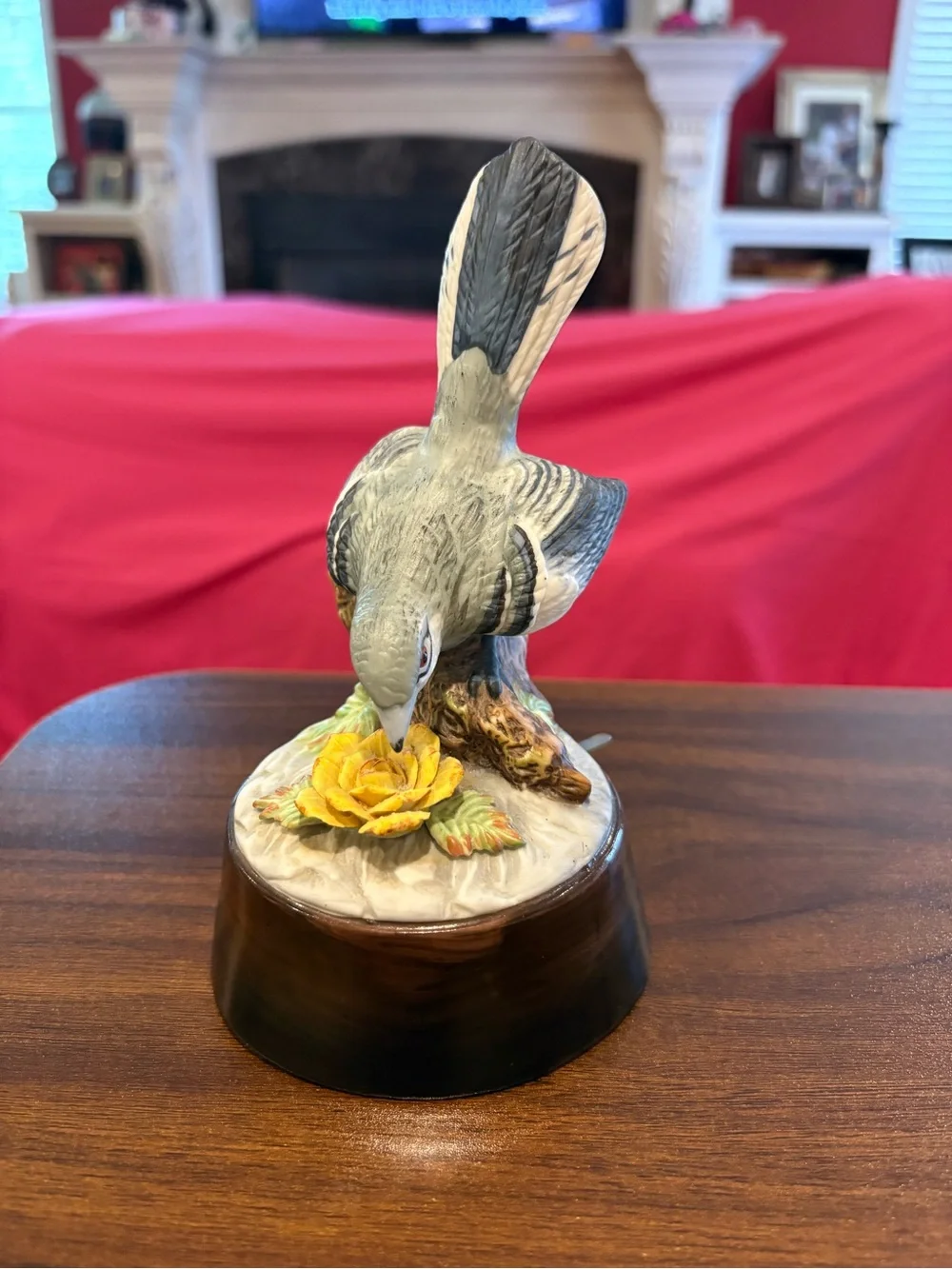 Vintage Grey northern mocking bird perched on a tree stump with yellow flowers.